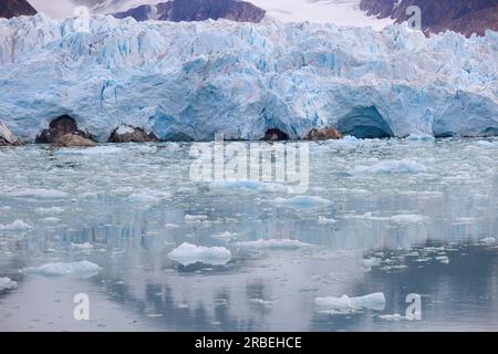 Gletscher in arktischen Gewässern mit schneebedeckten Bergen im Hintergrund Stockfoto