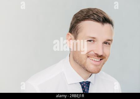 Positiver Unternehmer in eleganter Kleidung lächelt, freut sich über erfolgreiche Treffen mit Kollegen. Erörtert Geschäftspläne. Isoliert auf weißem Hintergrund. Stockfoto