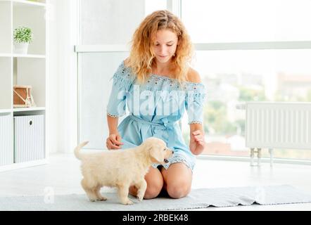 Glückliches Mädchen, das Welpen beibringt, zu Hause zu sitzen Stockfoto