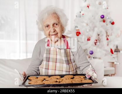 Seniorin hält Ofenkocher mit gebackenen Keksen Stockfoto
