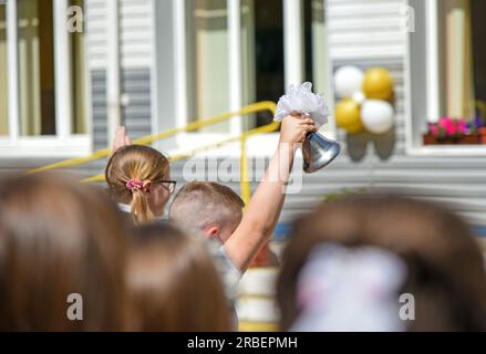 Kinder in der Schule tragen eine Glocke bei der ersten Glocke. Stockfoto