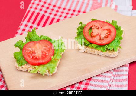 Reiskuchen-Sandwiches mit Tomaten und Salat auf Holzbrett. Einfaches Frühstück. Diät-Essen. Schnelle und gesunde Sandwiches. Knäckebrot mit leckerer Füllung. Gesunder Ernährungs-Snack Stockfoto