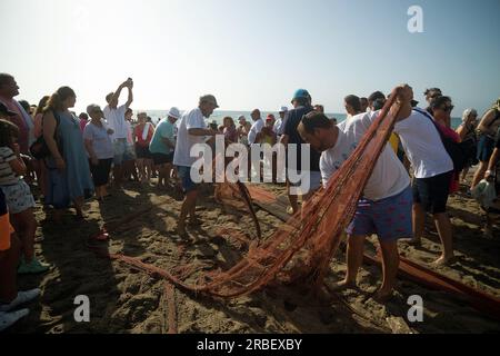 Malaga, Spanien. 09. Juli 2023. Die Einheimischen sehen, wie sie Netze entfernen, um Fische zu fangen, nachdem sie an der Ausstellung „La Tirada del Copo“ am Strand von Los Boliches teilgenommen haben. Jedes Jahr feiern die Einheimischen in Fuengirola eine alte Fischereitradition, bekannt als „La Tirada del Copo“, um die Fähigkeiten und den Handel von Seeleuten und Fischern beim Fang von Fischen im Meer zu demonstrieren. Wie es die Tradition vorschreibt, werfen Seeleute während der „La Tirada del Copo“ Netze ins Meer, die einen Halbkreis bilden, während andere die Netze zum Strand ziehen, um alle Fische zu fangen. Kredit: SOPA Images Limited/Alamy Live News Stockfoto