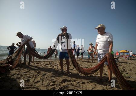 Malaga, Spanien. 09. Juli 2023. Die Einheimischen sehen, wie sie Netze entfernen, um Fische zu fangen, nachdem sie an der Ausstellung „La Tirada del Copo“ am Strand von Los Boliches teilgenommen haben. Jedes Jahr feiern die Einheimischen in Fuengirola eine alte Fischereitradition, bekannt als „La Tirada del Copo“, um die Fähigkeiten und den Handel von Seeleuten und Fischern beim Fang von Fischen im Meer zu demonstrieren. Wie es die Tradition vorschreibt, werfen Seeleute während der „La Tirada del Copo“ Netze ins Meer, die einen Halbkreis bilden, während andere die Netze zum Strand ziehen, um alle Fische zu fangen. Kredit: SOPA Images Limited/Alamy Live News Stockfoto