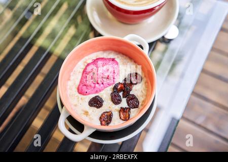 Frühstück mit frisch zubereitetem Haferbrei, serviert mit trockener Kirsche und Erdbeersorbet in der Schüssel. Müsli, köstliches Frühstück, Diät-Frühstück. Eine Tasse Stockfoto