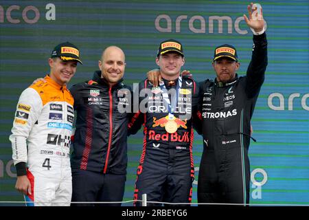 Red Bull's Max Verstappen (zweiter von rechts), Max Verstappen's Race Engineer, Gianpiero Lambiase (zweiter von links), McLaren's Lando Norris (links) und Mercedes' Lewis Hamilton posieren auf dem Podium nach dem britischen Grand Prix 2023 in Silverstone, Towcester. Foto: Sonntag, 9. Juli 2023. Stockfoto