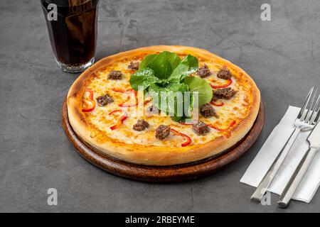 Pizza mit Paprika und Roastbeef auf dem Schneidebrett auf einem Steintisch Stockfoto