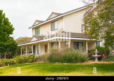 Ein altes Haus mit einer wunderschön gestalteten Vorderseite des Gartens und einem bewölkten Himmel im Hintergrund, irgendwo in Kalifornien Stockfoto