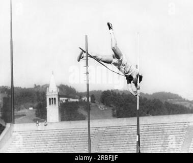 Berkeley, Kalifornien: ca. 1955 Ein Stabhochspringer trainiert im University of California Memorial Stadium mit dem Campanile im Hintergrund. Stockfoto