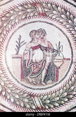 Dieses Foto eines Mosaiks, das ein Detail einer Schlafzimmerszene zeigt, wurde im Sommer 1970 auf der Piazza Armerina in Sizilien aufgenommen. Die Piazza Armerina beherbergt die römische Villa del Casale und ihre berühmten Mosaiken, die „besten Mosaike in situ in der römischen Welt“, wie von der UNESCO beschrieben, die sie 1997 in ihre Liste des Weltkulturerbes aufgenommen hat. Villa Romana war eine üppige Patrizier-Residenz, die im Zentrum eines riesigen Latifundiums (Landwirtschaftsgelände) am Ende des 4. Jahrhunderts n. Chr. erbaut wurde. Es wird angenommen, dass es einem Mitglied der römischen Senatorenaristokratie gehörte, der mit exotischen Tieren handelte. Die vi Stockfoto