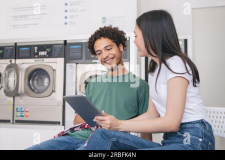 Mann Und Frau, Die Wäsche Mit Einem Digitalen Tablet Im Waschsalon Machen Stockfoto