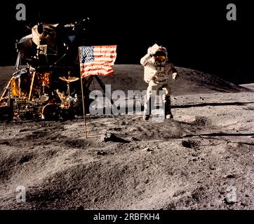 Mond: 21. April 1972 Astronaut John Young, Befehlshaber der Mondlandung Apollo 16, springt von der Mondoberfläche, während er während der ersten außerfahrbaren Aktivität der Mission vor der US-Flagge am Landeplatz der Descartes salutiert. Das Lunar Modul und das Lunar Roving Fahrzeug befinden sich auf der linken Seite. Stockfoto