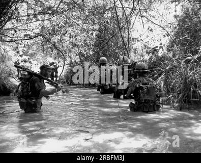 Vietnam: 12. August 1966 Marines of H Company, 4. Marine Regiment, umgehen Sie den dichten Dschungel und nutzen Sie einen Bach für eine Wanderung, während Sie sich während der Operation Hastings der nordvietnamesischen 324. Division stellen. Stockfoto