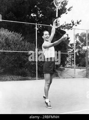 San Francisco, Kalifornien: Juni 1953 Model Evelyn Frey bereitet sich darauf vor, mit einem Lächeln in einer Tennisspielwerbung für Joseph Magnin zu dienen. Sie trägt ein kariertes Baumwollhemd, $4,95 Dollar und Gabardineschnitte, $3,95. Stockfoto