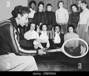 New York, New York: Dezember 1957 Althea Gibson, US- und Wimbledon-Tennismeisterin, gibt Schülern, die eine Tennisklinik an der Midwood High School in Brooklyn besuchen, einige Hinweise zum Spiel. Stockfoto