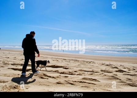 Ein Mann geht mit seinem Hund an einem Strand in Pismo Beach, Kalifornien. Stockfoto