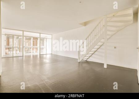 Ein leeres Wohnzimmer mit Treppen bis zum zweiten Stock und Glastüren, die auf den Balkon führen Stockfoto