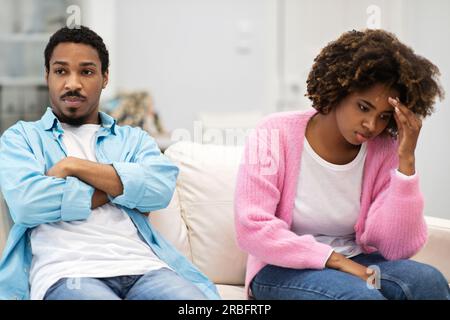 Ein dickköpfiges schwarzes Paar sitzt nebeneinander auf der Couch Stockfoto