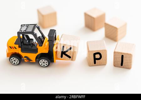 Spielzeug Gabelstapler halten Holz schreiben Block I zu Wort vervollständigen KPI (Abkürzung von Key Performance Indicator) auf weißem Hintergrund Stockfoto