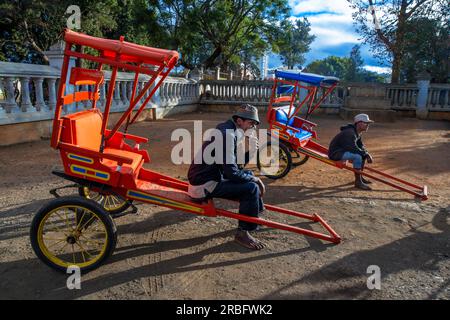 Farbenfrohe Rikschas warten auf Kunden in Antsirabe, Region Vakinankaratra, National Road 7, Madagaskar. Die Rikscha oder Position ist die breiteste Stockfoto