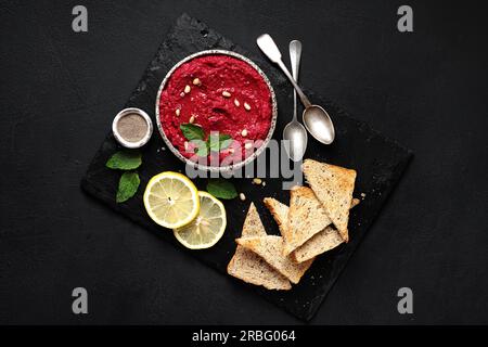 Gesunder hausgemachter Rote-Bete-Dip oder Hummus mit Brot, dunkler Hintergrund, Draufsicht Stockfoto