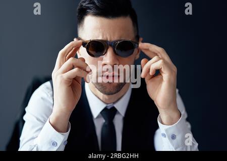 Schönen eleganten Mann in retro Sonnenbrille im Studio posiert auf schwarzem Hintergrund Stockfoto