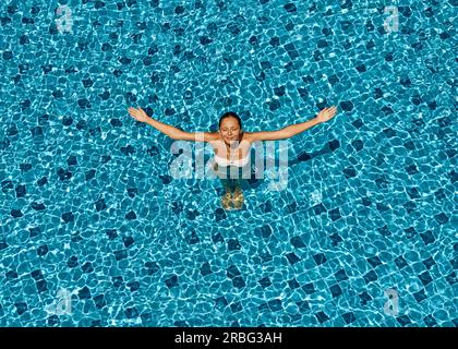 Blick von oben auf die glückliche Frau erhobenen Armen zu Sonne entspannen im Pool. Sommer Urlaub Konzept Stockfoto