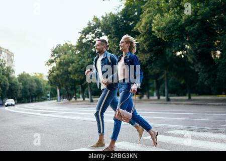 Junge glücklich Paar, dass Zebrastreifen auf der Straße. Spaß, Wandern, dating Konzept Stockfoto