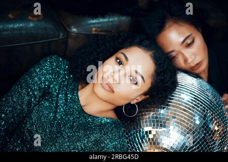 Eine hübsche junge afrikanerin, die sich nach einer verrückten Party auf dem Boden auf dem Discoball in einem Nachtclub entspannen kann. Neujahr, Geburtstag, Feiertagsveranstaltung, Spaß Stockfoto