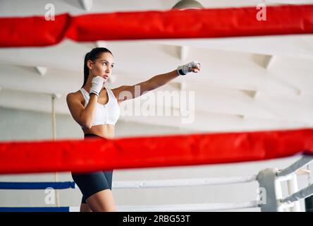 Eine Boxerin übt ihre Schläge in einem Boxstudio. Eine sportliche Frau, die direkt zuschlägt. Sportkonzept Stockfoto
