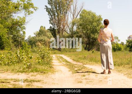 Eine Frau mit einem chignon, die stehen in der Nähe der Landstraße in Kiew, Ukraine, beobachtet die Bäume in der Ferne. Die Silhouette der Dame ist Aus Stockfoto