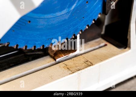 Metallsäge mit Werkzeugtrennscheibe schneidet. Arbeiten in der Heimwerkstatt mit einer elektrischen Stahlschneidmaschine. Funken aus dem Winkelschleifen unter der Trennscheibe Stockfoto