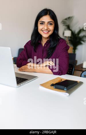 Vertikale Aufnahme einer jungen indischen Frau, die zu Hause mit einem Notebook arbeitet Stockfoto