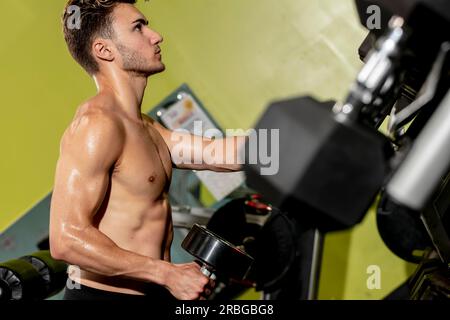 Ein Mann trainiert in einem örtlichen Fitnessraum mit stationären Geräten Stockfoto