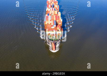 Ein Frachtschiff dampft aus einem Hafen in Richtung des offenen Ozeans Stockfoto