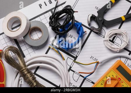 Verschiedene Drähte, Werkzeuge und elektrische Pläne auf grauem Tisch, Nahaufnahme Stockfoto