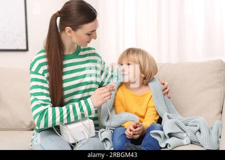 Mutter hilft ihrem kranken Sohn bei der Inhalation von Verneblern zu Hause Stockfoto