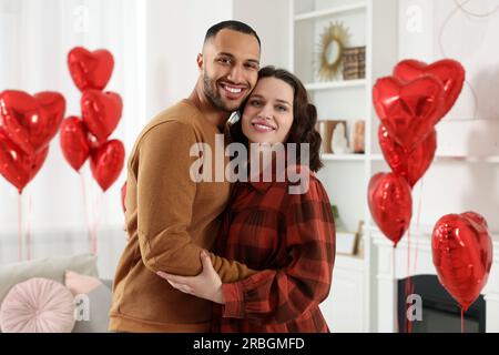 Ein reizendes Paar im Zimmer, das mit herzförmigen Luftballons dekoriert war. Valentinstag-Feier Stockfoto