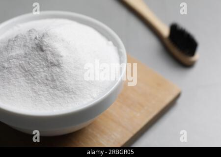 Bambuszahnbürste und Schüssel mit Backpulver auf grauem Tisch, Nahaufnahme. Platz für Text Stockfoto