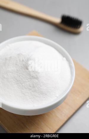 Bambuszahnbürste und Schüssel mit Backpulver auf grauem Tisch, Nahaufnahme Stockfoto