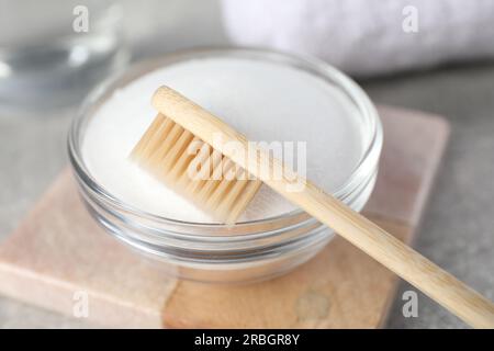 Bambuszahnbürste und Glasschüssel mit Backpulver auf einem leichten Tisch, Nahaufnahme Stockfoto