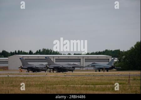 Zwei US-Dollar Air Force F-16cm Kampfflugzeuge der Falcon, die dem 148. Kampfflug der Nationalgarde Minnesota zugewiesen sind, sind startbereit, während ein deutscher Eurofighter Typhoon die Fluglinie am Tactical Air Force Wing 73, Laage, Deutschland, während der Übung Air Defender 2023 (AD23), 19. Juni 2023, herunterfährt. Übung AD23 ist eine multinationale Übung unter deutscher Leitung, die sich auf operative und taktische Feldschulungen konzentriert und vor allem in Deutschland durchgeführt wird, wobei sich die Einsatzorte in der Tschechischen Republik, Estland und Lettland befinden. (USA Air National Guard Foto von Tech. Sgt. Sarah M. McClanahan) Stockfoto