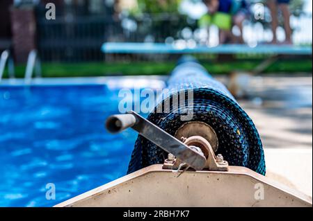 Manuell wirkend für eine einziehbare, schwimmende Poolabdeckung, um Blätter fernzuhalten und Wärme zu halten. Stockfoto