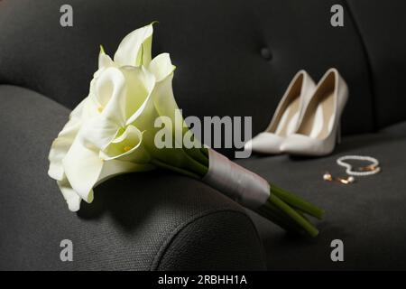 Wunderschöne Calla-Lilien-Blumen mit Band, Schuhen und Schmuck auf dem Sofa Stockfoto