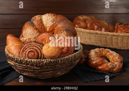 Korbkörbe und verschiedene leckere, frisch gebackene Backwaren auf einem Holztisch Stockfoto