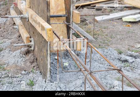 Nahaufnahme der Betonfußzeile in Platten. Betonfußböden in Holzplatten mit Bewehrungsstäben für neue Hausfundamentzäune eingießen. Stockfoto