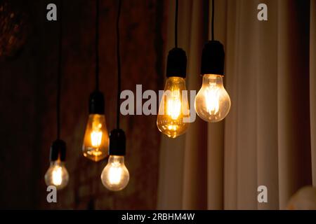 Lampen im Retro-Stil hängen in der Nähe der alten Backsteinmauer in Stimmung, Retro-Beleuchtung, Inneneinrichtung, Retro-Glühbirne Stockfoto