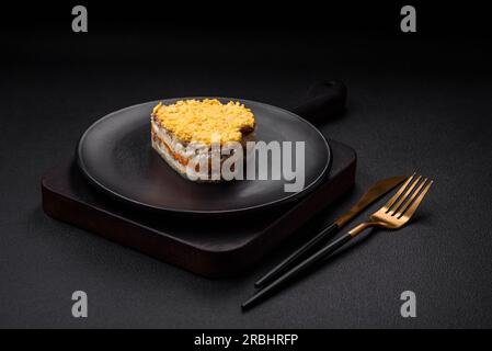 Köstlicher frischer Mimosesalat mit Fischkonserven, Eiern, Moinese, Käse, Salz und Gewürzen auf dunklem Betonhintergrund Stockfoto