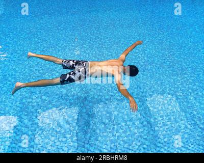 Ertrunkener Mann schwimmt im Wasser des Hallenschwimmbeckens, konzeptionelle Aufnahme Stockfoto