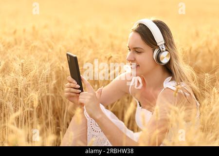 Glückliche Frau, die Musik in einem goldenen Weizenfeld hört Stockfoto